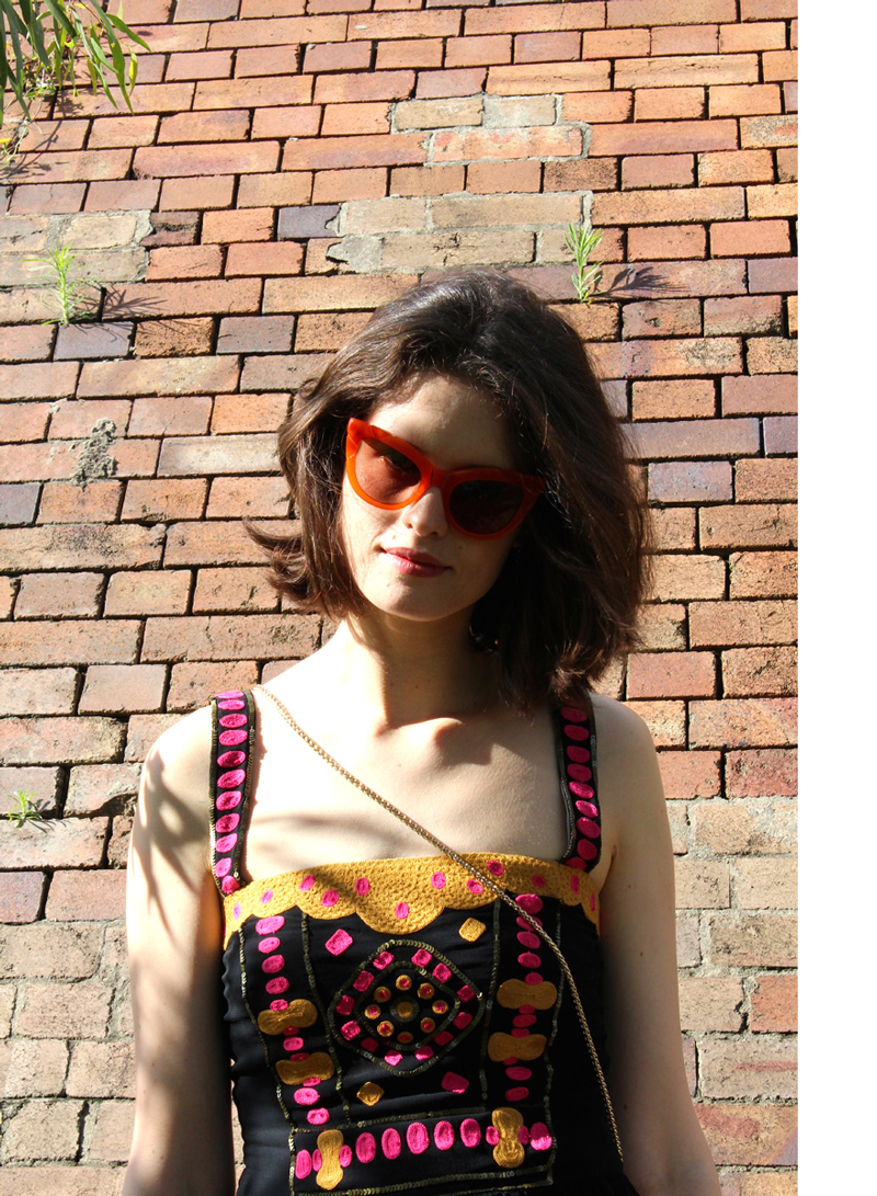 Chloe-Hill-Wearing-Easton-Pearson-yeloow-and-pink-beaded-top-and-pared-orange-cateye-sunglasses-border